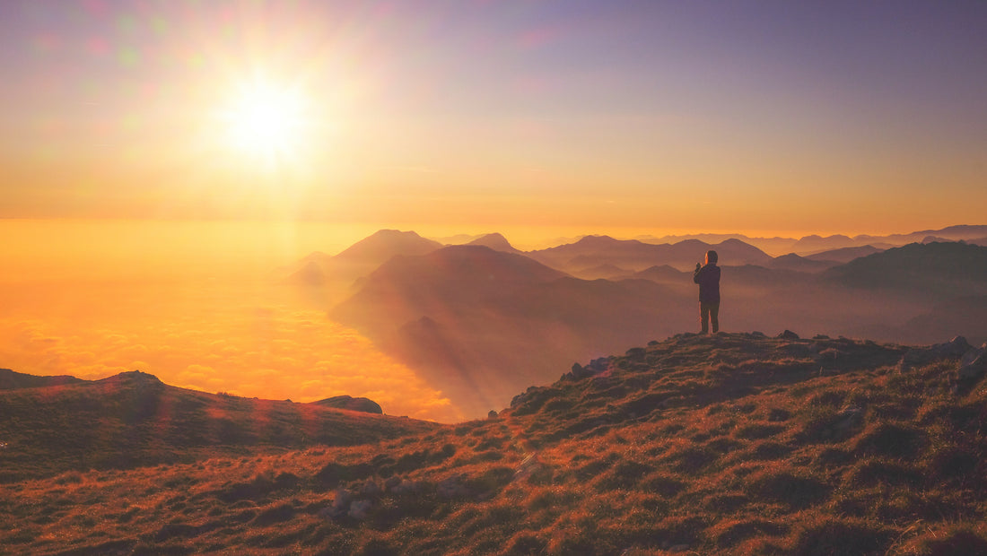 person standing on mountain at sunset photo by Cristina Gottardi on Unsplash